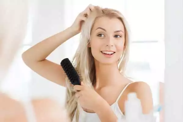 Applying perfume in hair by spraying on brush